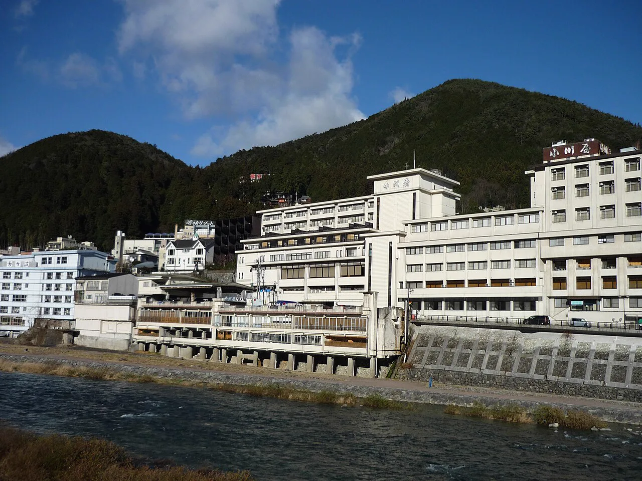 由下呂大橋方向看到的下呂溫泉街，說明飛驒川兩岸旅館與鐵道共存的住宿環境